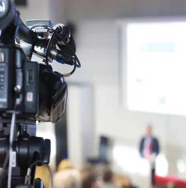 Official media briefing with journalist questioning, broadcast press setup, and communication control environment
